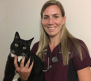 Dr. Deanna White, Emergency Veterinarian at Boundary Bay Veterinary Specialty Hospital, smiling in burgundy scrubs with a black and white cat