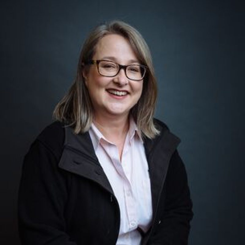 Dr. Sarah Charney, DVM, DACVIM (Oncology), DACVR (Radiation Oncology), Board-certified Oncologist, smiling in a professional portrait with a dark background.