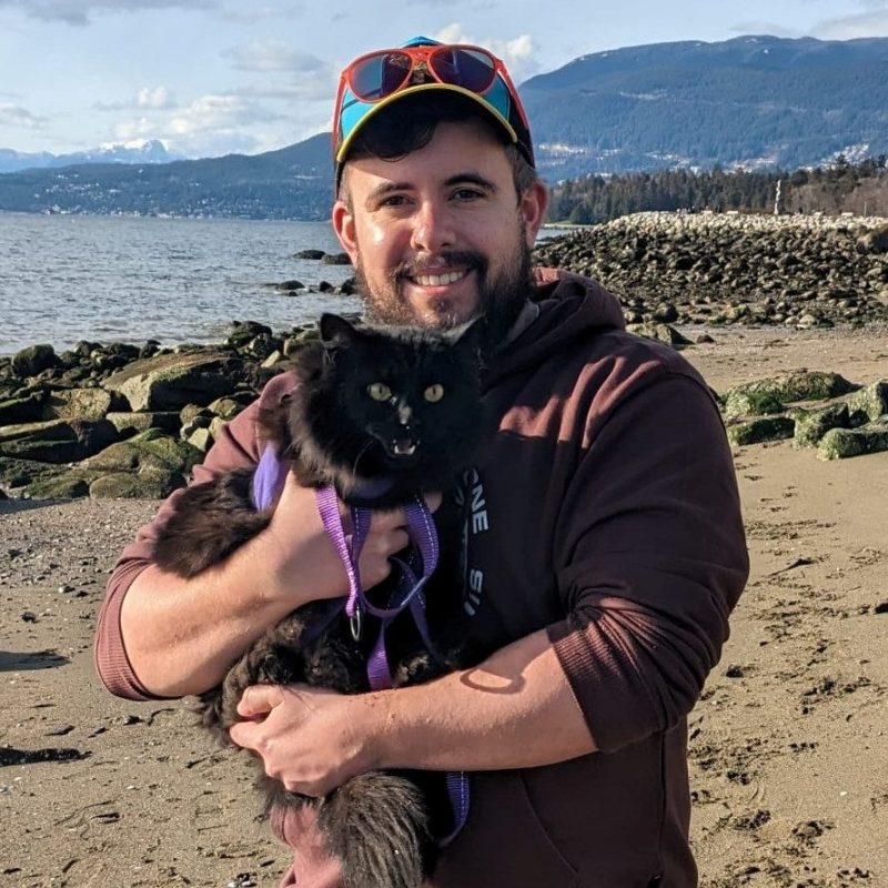 Dr. Tim Donihee, Emergency Veterinarian at Boundary Bay Veterinary Specialty Hospital, holding a cat on a beach