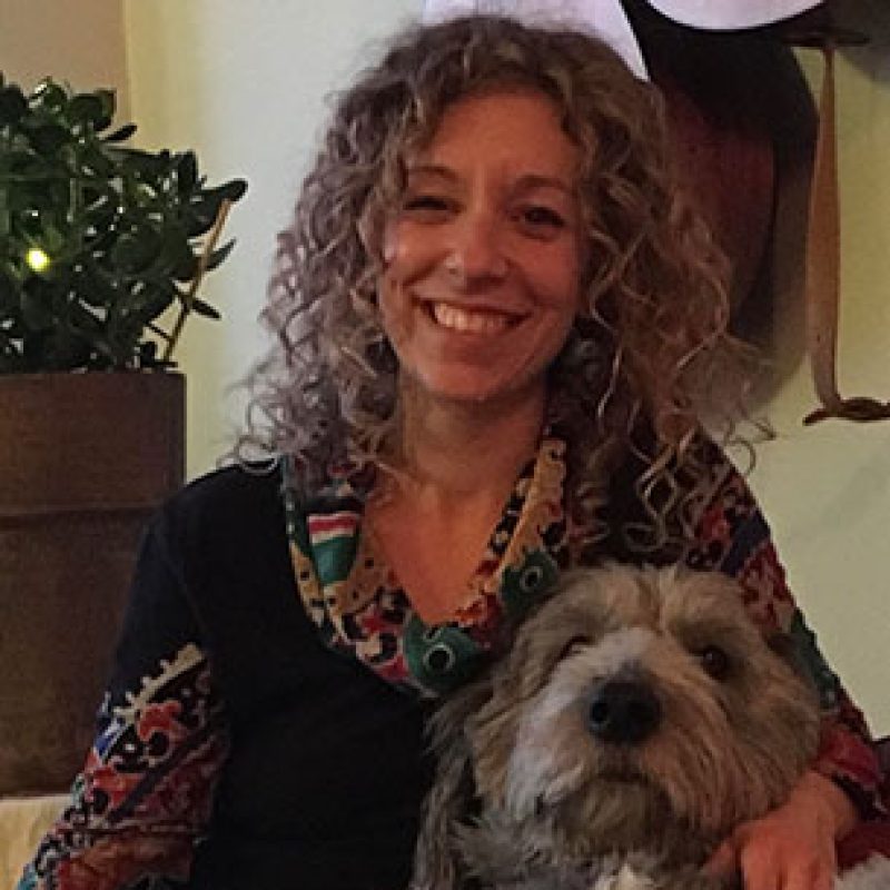 Dr. Emily Vogt, Emergency Veterinarian at Boundary Bay Veterinary Specialty Hospital, smiling while holding a dog indoors