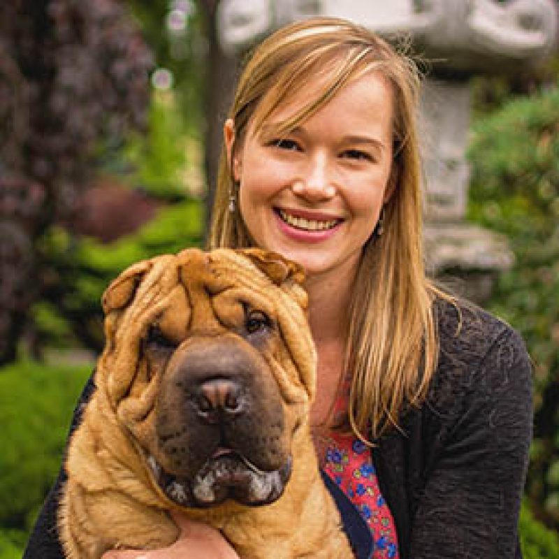 Dr. Jillian Thatcher, Emergency Veterinarian at Boundary Bay Veterinary Specialty Hospital, smiling while holding a Shar Pei dog outdoors